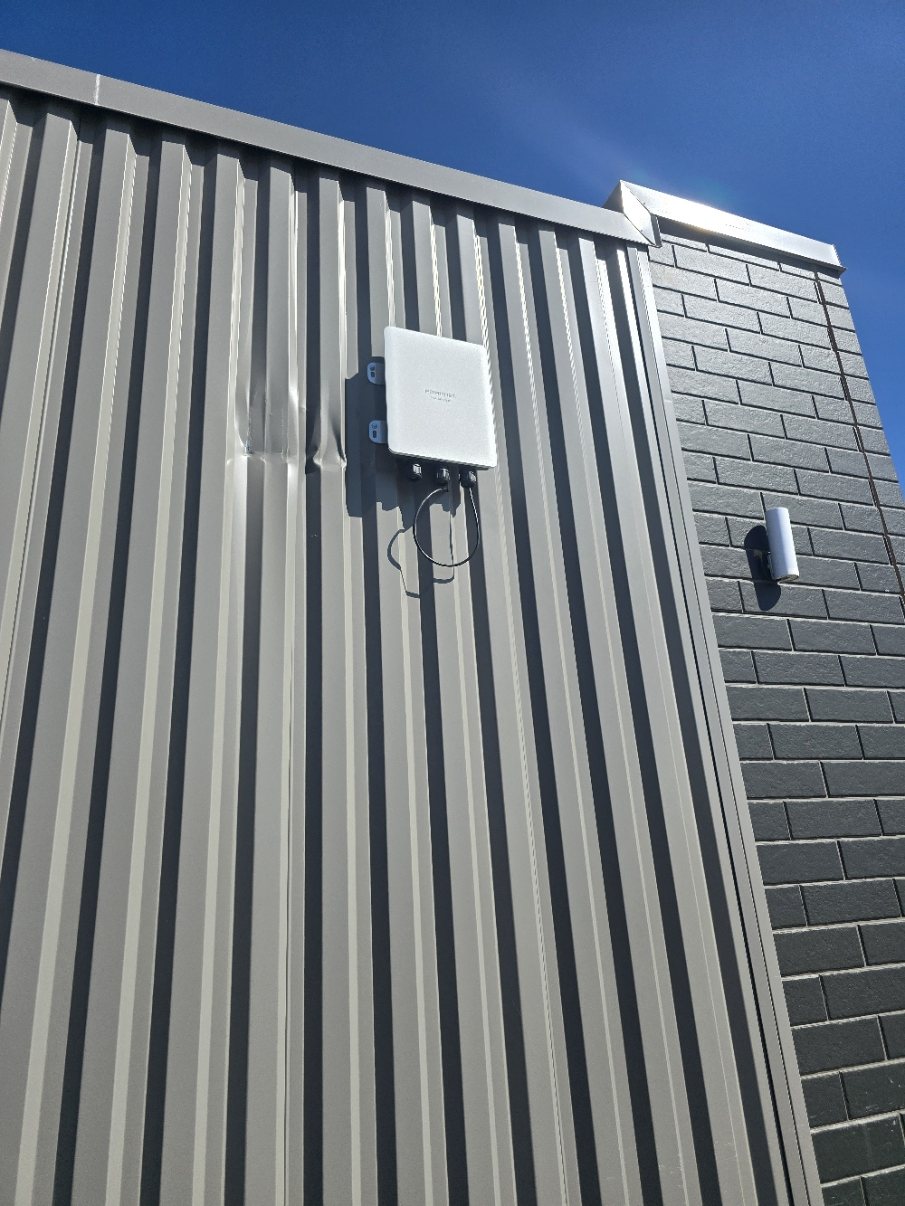 Exterior rooftop wireless or camera mount with clean cable pathway on a commercial building