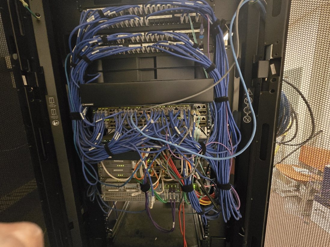 Structured cabling rack with organized blue Cat6 patch cables and commercial network equipment in West Texas